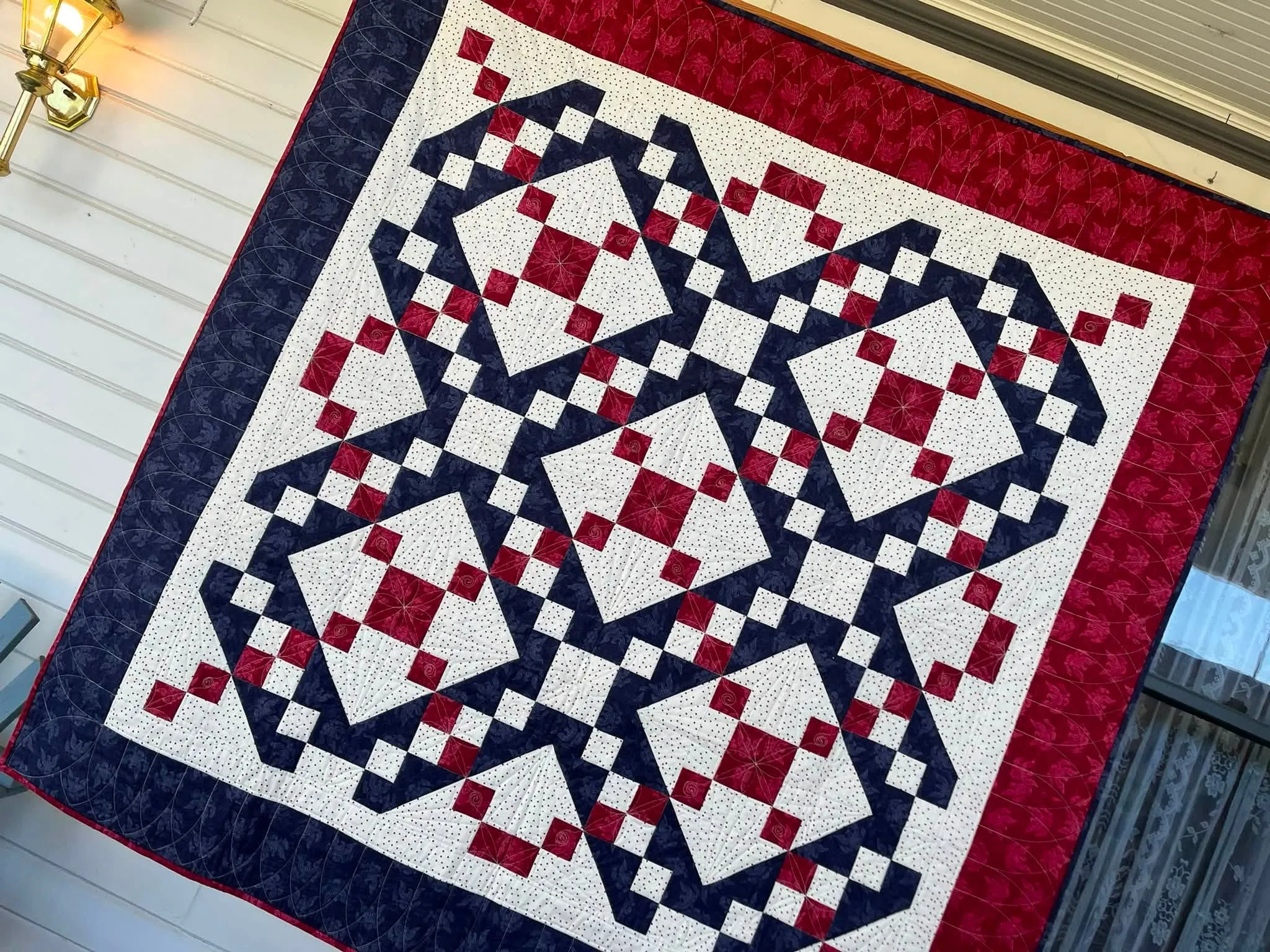 Navy and burgundy chain-and-star medallion quilt on a cream background
